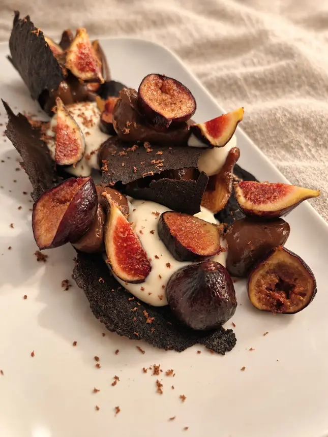 Figues, crème et croustillant au chocolat sur une planche sombre